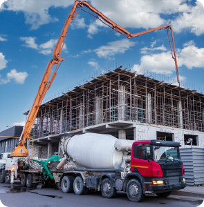 Construction site with red concrete mixer truck and crane, supported by sweet water tanker supply under a clear blue sky.